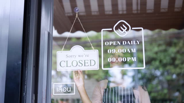 Young attractive woman in casual uniform turning closed sign to open on front door.