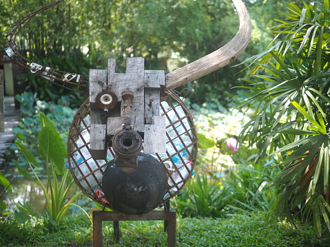 Recycled plastic bottle bin in the shape of a cow fashioned from scrap metal, nuts and bolts, and planks of wood