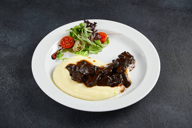istock Braised beef cheeks over creamy mashed potatoes, a gourmet dish featuring tender meat with rich gravy 2130466546
