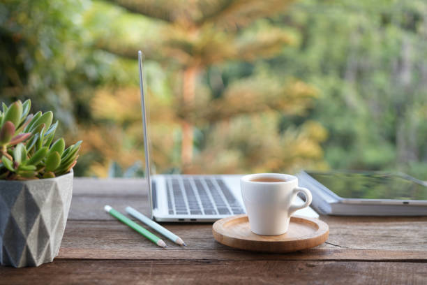 istock Laptop side view and coffee cup with notebooks on white table outdoor 2130492037