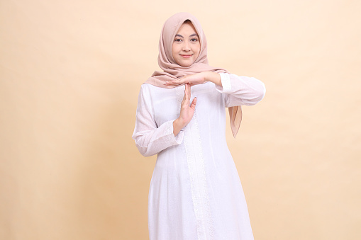 young asian muslim woman standing smiling hand gesturing time is up. Fashion, pointer, business and promotion concept