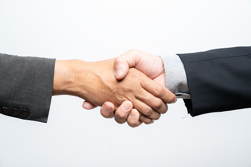 Handshake of two businessmen on the background of bright boardroom, partnership concept, close up