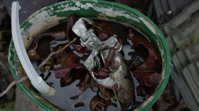 Bucket of rusty metal screws and plastic in water. Abandoned objects