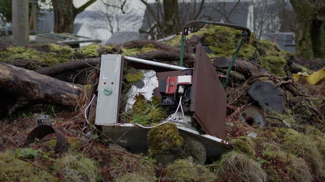 Abandoned washing machine overgrown by nature with moss. Pollution from object dumped on land
