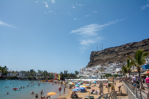Puerto de Mogán, Gran Canaria, Spain, September 1st, 2023 - Sandy beach in the city with lots of people and blue sky