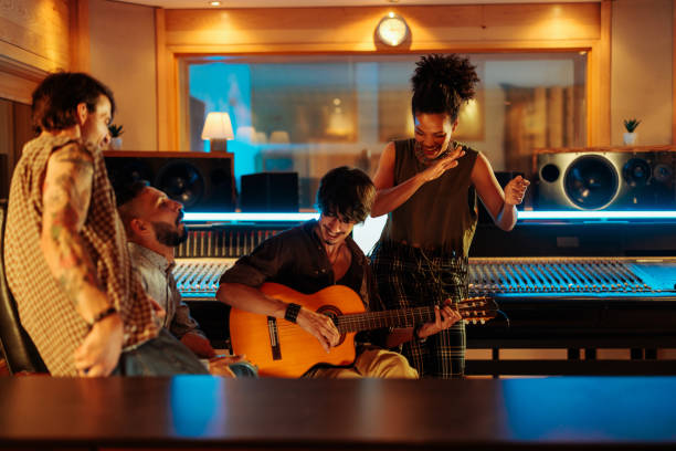 istock Four friends playing instruments and singing in the music studio 2130556879