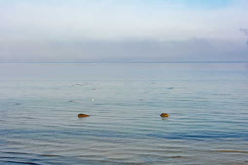 Big rock with stones lie in the calm water on the coast of the Baltic Sea