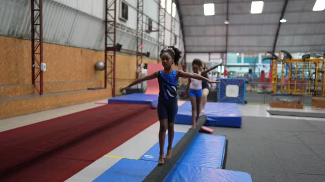 Gymnast girl walking on the balance beam in a gymnasium