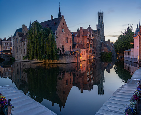 Bruges, Belgium - July 06, 2023: Famous Rosary Quay (Rozenhoedkaai) in the most popular waterway canal in the old town of the beautiful city of Brugge in Belgium at night, with its historic facades.