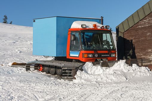 Red snowcat,  fully tracked vehicle designed to move on snow in front of ski lodge in krkonose mountains, Czech Republic.