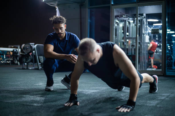 istock Man Performing Push-Ups at Night in a Well-Equipped Gym Under Supervision 2130652704