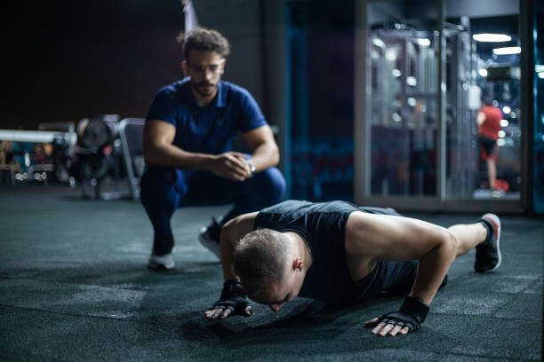 istock Man Performing Push-Ups at Night in a Well-Equipped Gym Under Supervision 2130653227