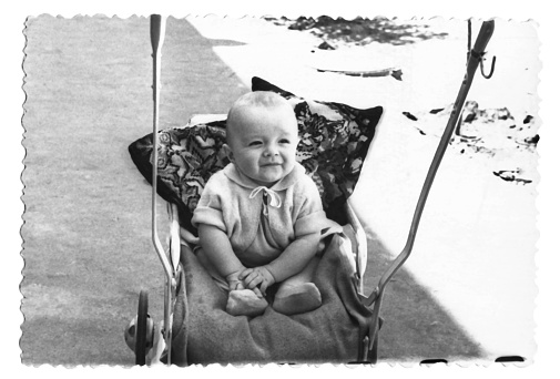 Vintage photo of a boy in a stroller. The child smiles. Photo from 1961.