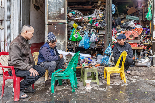 Hanoi, Vietnam - March 19, 2024: Old handyman repairs used electrical appliances on the street in downtown Hanoi