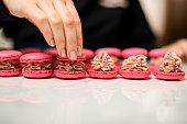 Close-up side view of red macaroons, on each of which beige cream of a curvy shape is applied