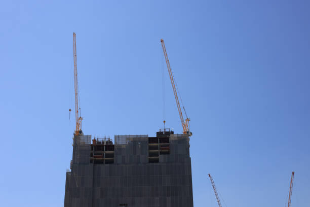 istock Two construction cranes are positioned on top of a newly constructed building, symbolizing business investment 2130757388
