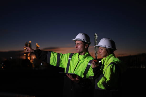 istock Two engineers wearing green reflective safety suits are diligently working late into the night at the construction site. 2130758946