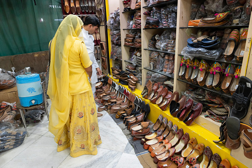 Jodhpur, Rajasthan, India - 15.10.2019 : Pairs of Rajasthani mens' and womens' shoes at display for sale. Jaisalmer, Rajasthan, India. rajasthani man and woman trying out shoes to buy.