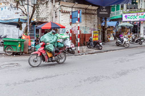 A Vietnamese man transports numerous bags on a motorcycle to Hanoi, Vietnam