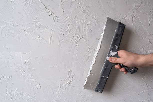 Applying decorative putty. White abstract texture of surface covered with putty Applying decorative putty. White abstract texture of surface covered with putty. textured background of filler paste applied with putty knife in irregular dashes and strokes. Rough surface plaster hand with a plaster spatula stock pictures, royalty-free photos & images
