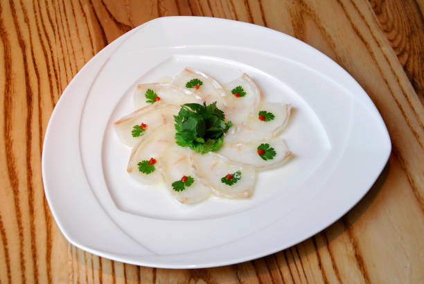istock fish carpaccio garnished with coriander leaves and tomato chunks on wooden table 2130864765