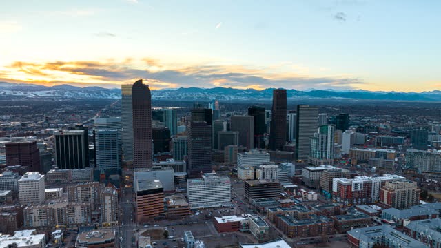 Drone hyperlapse dolly view of Denver CBD skyline at sunset with Rockies in back