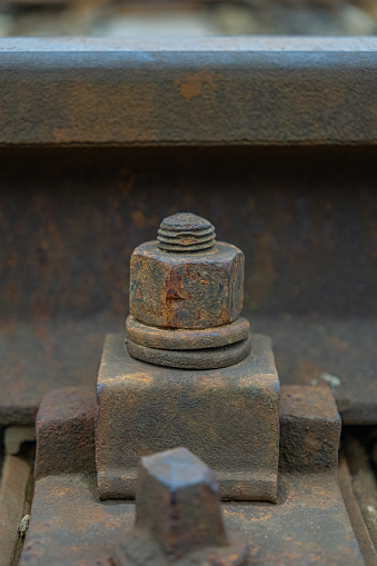 Old rusty screw that holds the rail. Old railway parts, close-up with selective focus