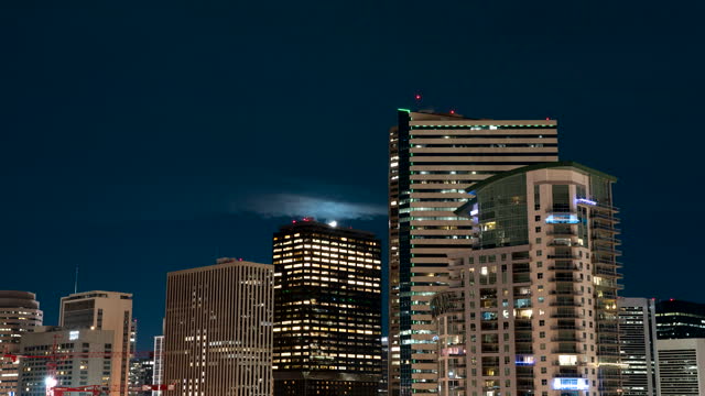 Zoom motion timelapse of moonset over illuminated skyscrapers on Denver skyline