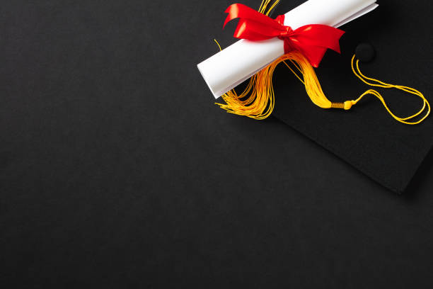 istock Graduation cap and a rolled diploma on black background. Flat lay, top view. 2130871662