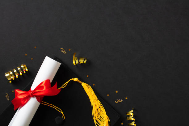 istock Graduation cap and diploma on black background. Flat lay, top view. 2130874805