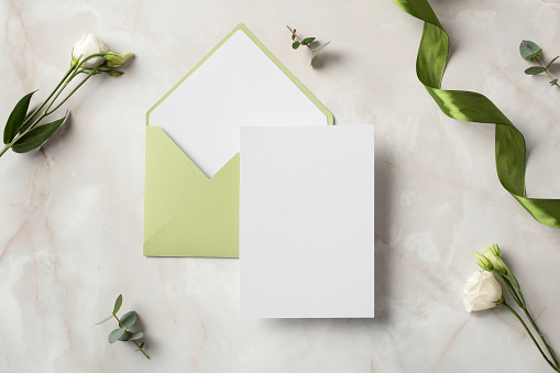 Wedding invitation card mockup with olive envelope on stone table top view.