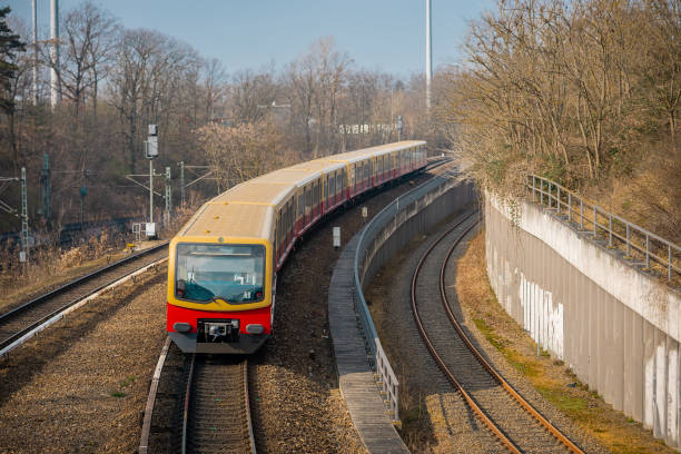 S bahn or suburban trains in Berlin, Germany. Modern red and yellow train for commuting purposes, on station of Messe Sud on a sunny spring day. Rear view