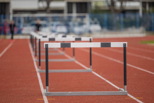 istock Hurdles for athletic running standing in a row. Open space on stadium, running track with a row of hurdles. Sunny day, person in bokeh in the background 2130891588