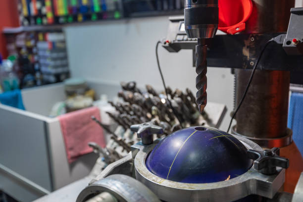 Drilling holes with a drill bit into bowling ball. Preparing bowling ball for a customer, custom holes with special size and diameter into a ball.