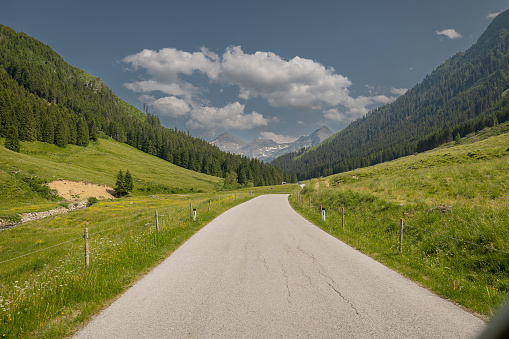 The road towards the Solkpass in austria, one of the mountian passes if you want to evade tunnels or obertauern. Green hills and some clouds, pass in the background.