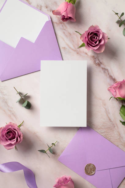 istock Wedding invitation card mockup, purple envelope and roses marble background. Flat lay, top view, copy space. 2130892667
