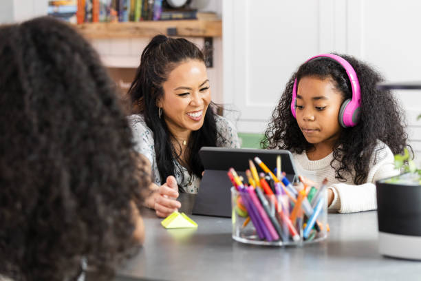 istock Unrecognizable child works independently while mom and sister use tablet 2130892910
