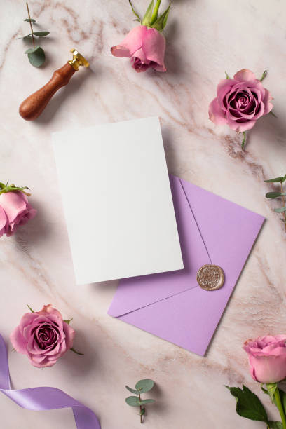 istock Wedding invitation card template with violet envelopes and roses on marble background. Top view, flat lay. 2130899049
