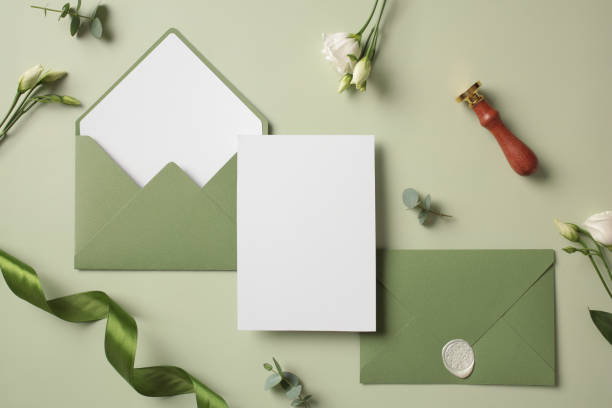 istock Flat lay composition with wedding invitation template and green envelopes on green background 2130902881