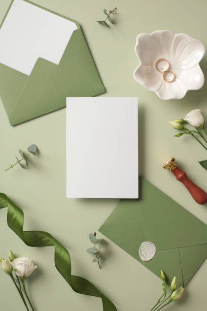 istock Wedding flat lay composition with blank paper card wedding invitation mockup, green envelopes, gold rings, wax seal stamp, flowers on pastel green background 2130906612