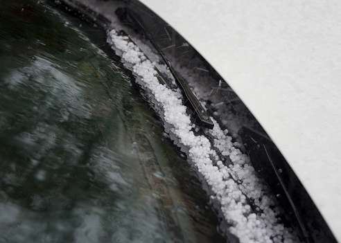 Detail of solid hail on a car's windshield wiper.