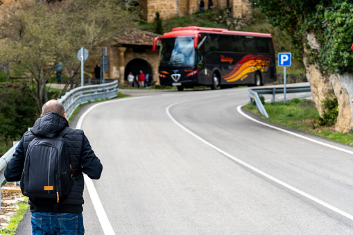 Tourist walks towards a coach in the town of Tobera in the province of Burgos, Castilla y Leon - Spain.