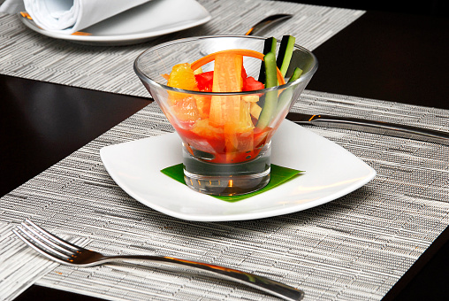 fruit and vegetable salad in a glass on a wooden table and tablecloth in a restaurant