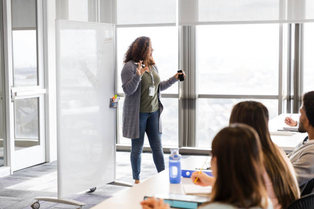 istock Mid adult female professor gestures while talking to her class 2130940646