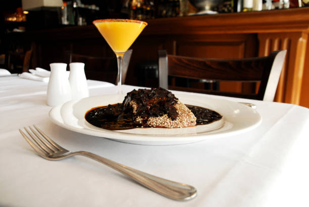 istock Mole poblano, plate of mole with sesame seeds on a restaurant table accompanied by a cocktail, typical Mexican dish 2130968160