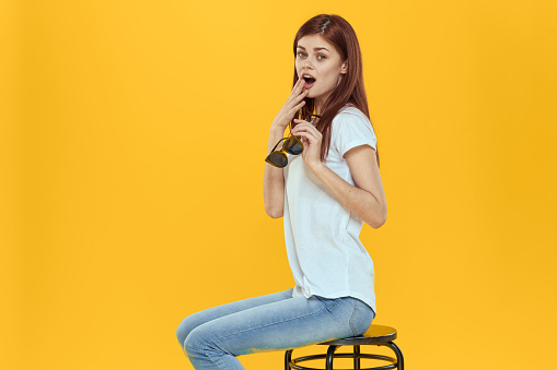 Pretty woman sitting on a chair fashionable clothes lifestyle yellow background. High quality photo