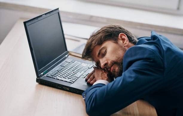 istock Man in a suit at a working table in front of a laptop office tired 2131037902