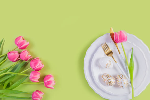 istock Pink tulips, table place setting and festive easter decor on pastel green background 2131069851
