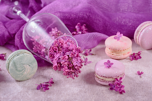 Sweet pastel french macaroons and lilac flowers on light gray background. Beautiful composition for bakery and pastry shop