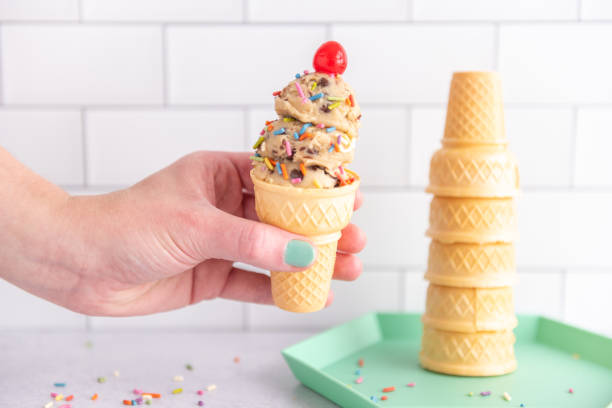 istock Woman's hand holding an ice cream cone with a cherry on top 2131134539